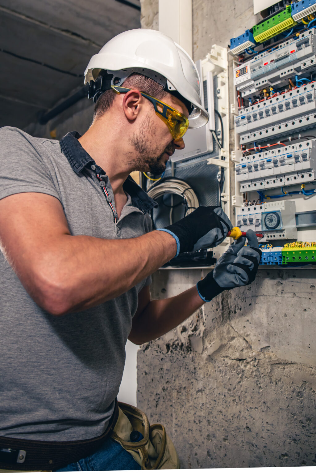 Man, an electrical technician working in a switchboard with fuses. Installation and connection of electrical equipment. Professional uses a tablet.